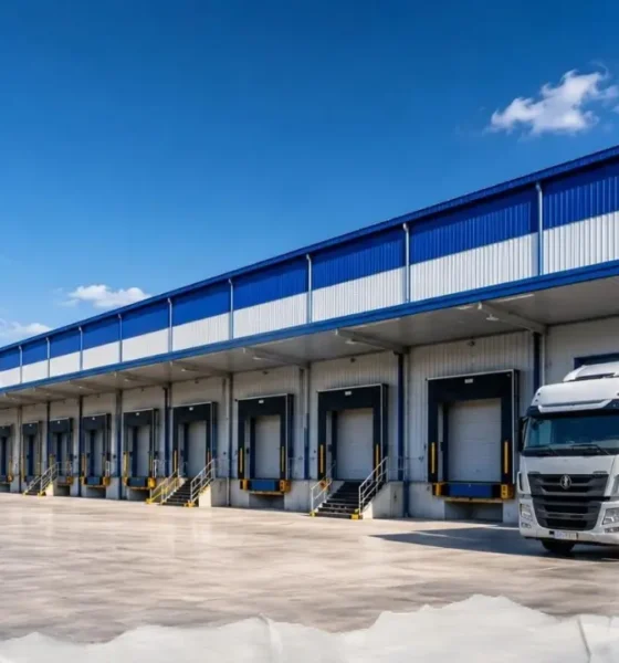 Representative image of a modern logistics warehouse with freight trucks