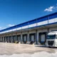 Representative image of a modern logistics warehouse with freight trucks